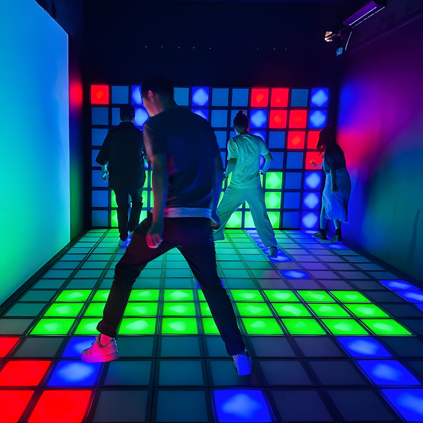 People playing on a large interactive grid floor with glowing tiles.
