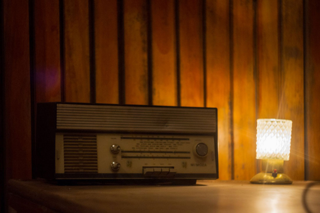 A vintage radio and a small lamp on a wooden table, evoking a spy thriller atmosphere.